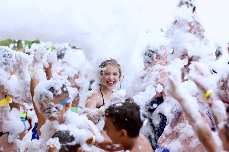 Group of people having fun, enjoying and dancing at a foam party in aquapark. N